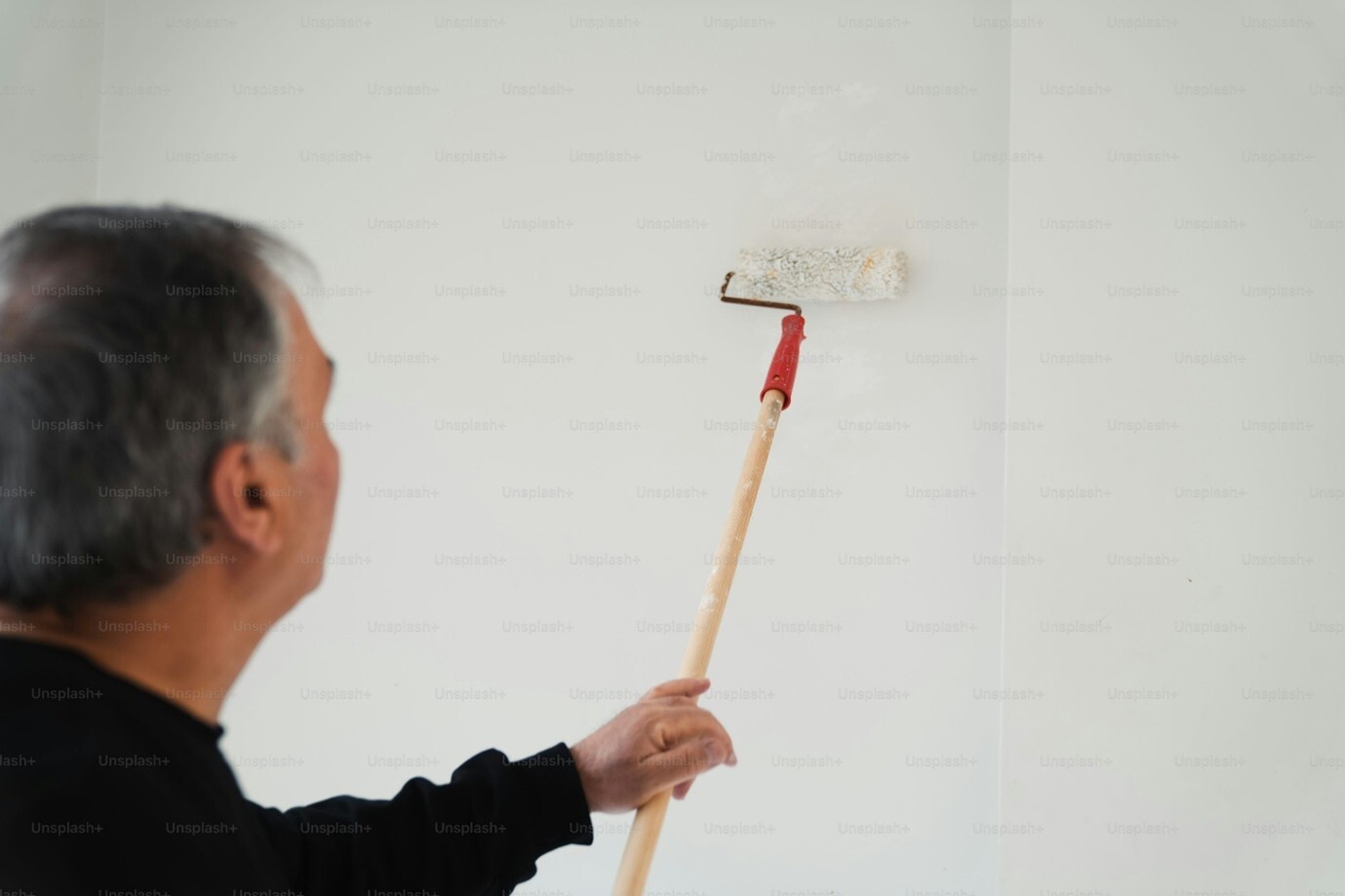 Man painting a wall with a roller