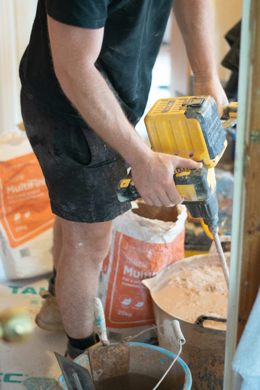 A man mixing plaster in a bucket with a drill and mixer